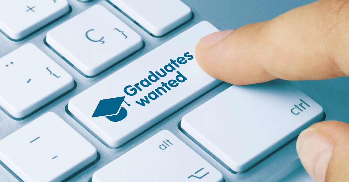 A finger presses down on a key on a white keyboard. The key reads "graduates wanted" with a graduation cap next to the words.