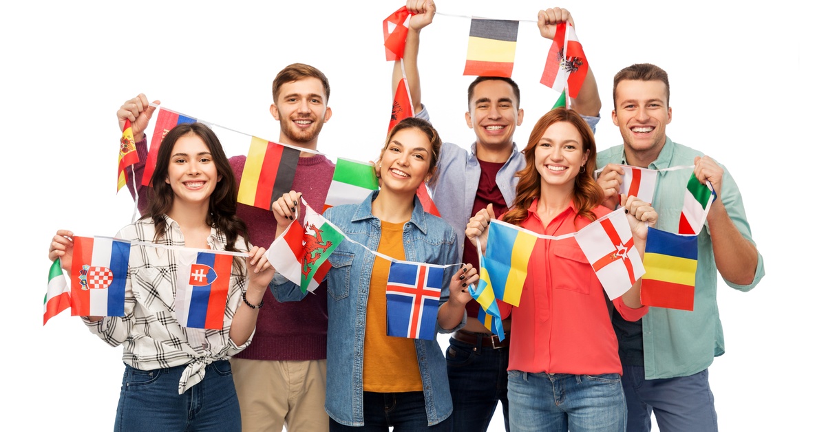 A group of people standing together holding the flags of different countries on strings, against a plain white background.