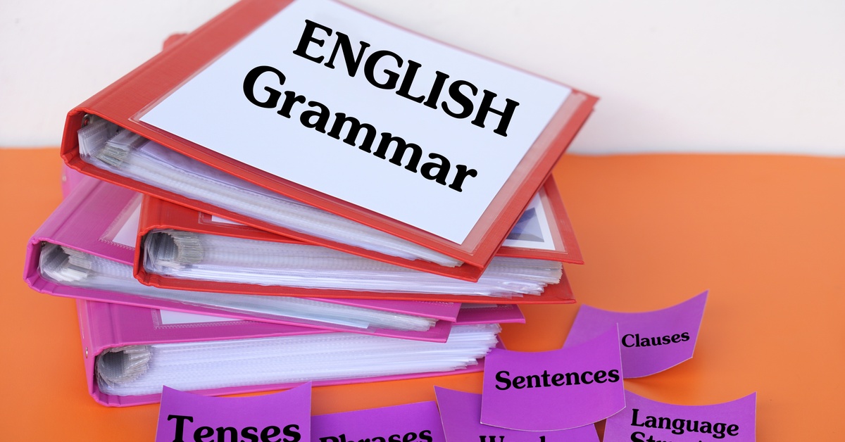 Stacks of colorful binders labeled "English grammar" and flashcards with the words "tenses," "phrases" and more on them.