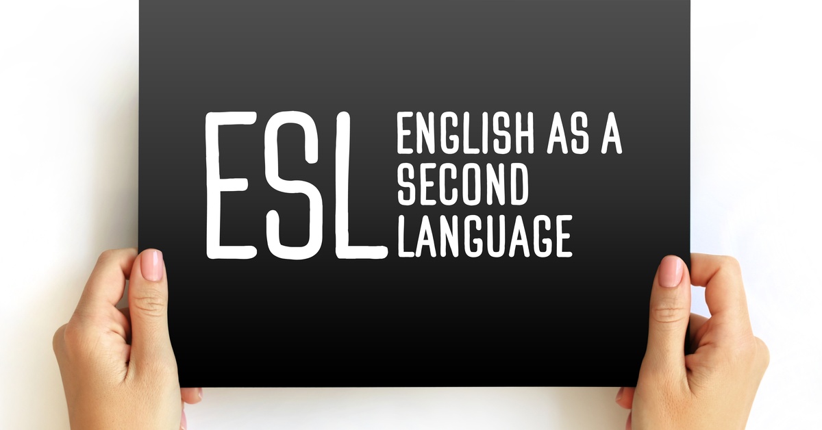 A person's hands are holding a black card with the phrase "ESL English as a Second Language" written on it in white letters.