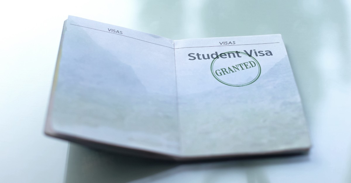 A small book turned to a page labeled "student visa," with the word "granted" stamped on it, against a plain background.