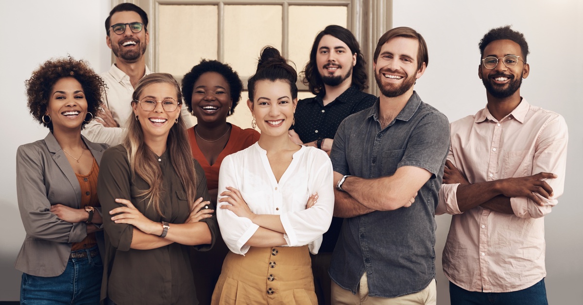 Happy, diverse, smiling group of startup entrepreneurs standing together, arms folded, for a professional photo.