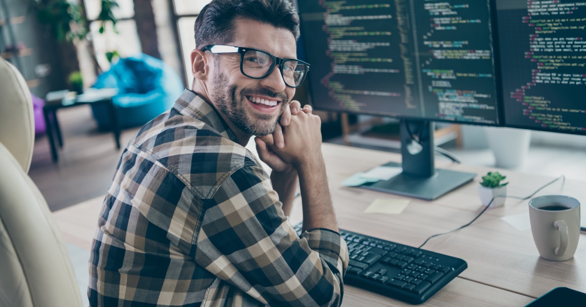 A cheerful, intelligent web designer sits in a chair, creates a project, and works in an open workplace.