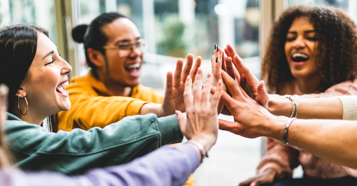 A group of happy young people having fun together indoors at a table in a community center or career services.