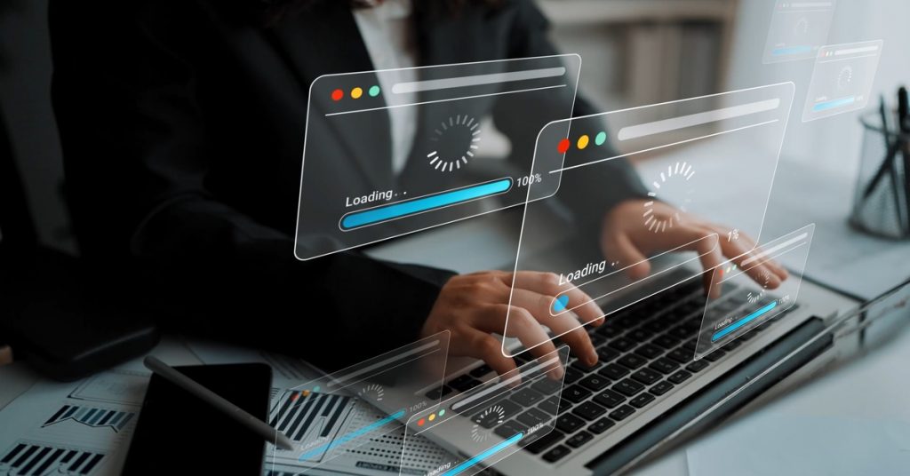 Hands type on a laptop with digital progress bars and loading windows layered over the office scene.
