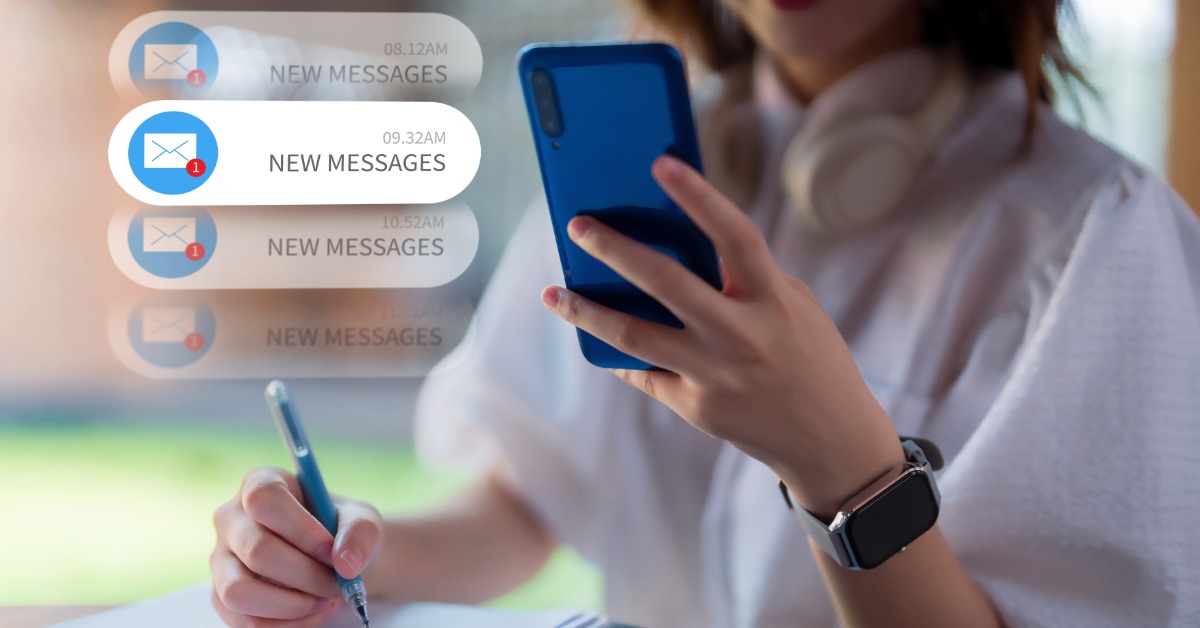 Woman holds a phone and pen over a clipboard as several new message alerts appear alongside her on screen.